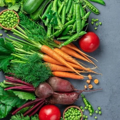 fresh-carrots-zucchini-peas-tomatoes-and-greens-on-a-dark-blue-background-top-view-copy-space_166116-3480